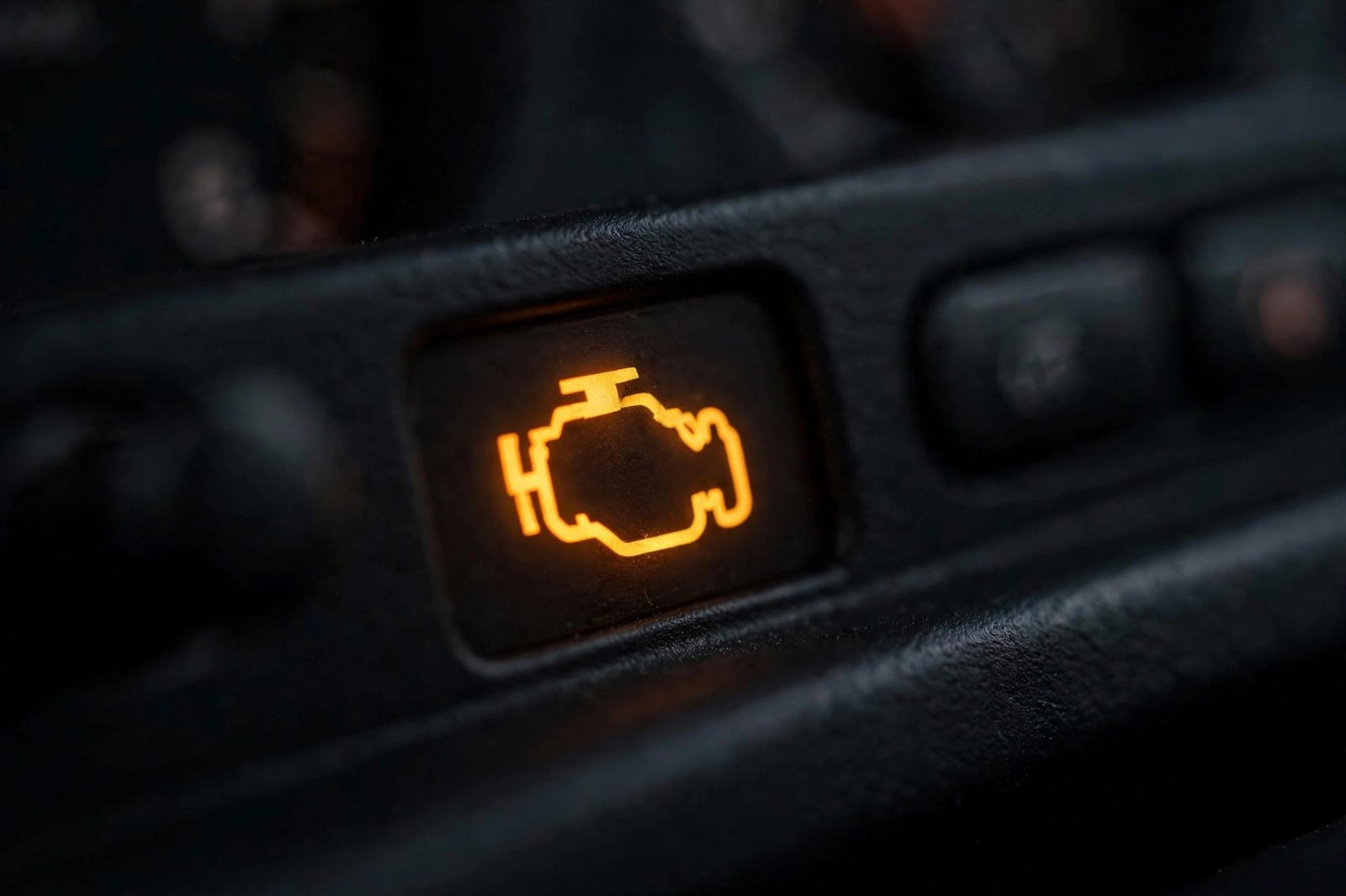 Glowing amber check-engine warning light on a car dashboard